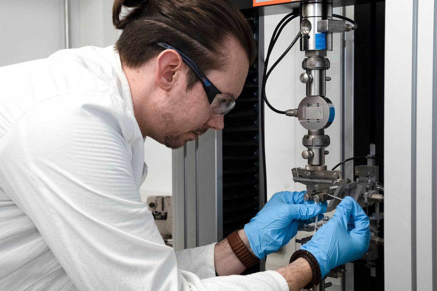 A man in a laboratory tests something on a tensile shear machine
